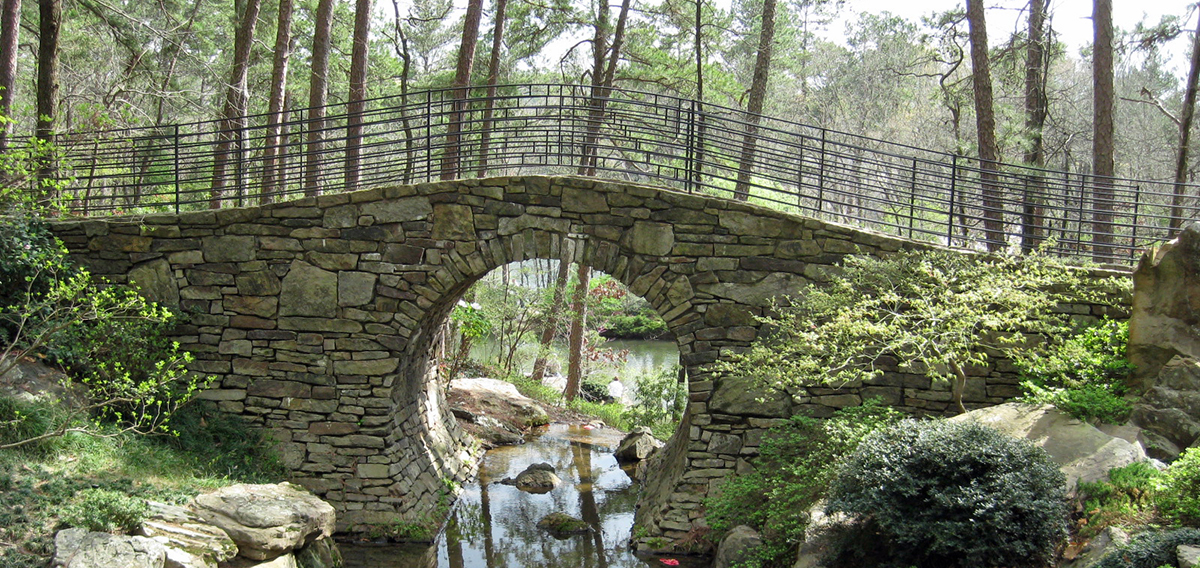 A bridge spans a stream in a wooded spot